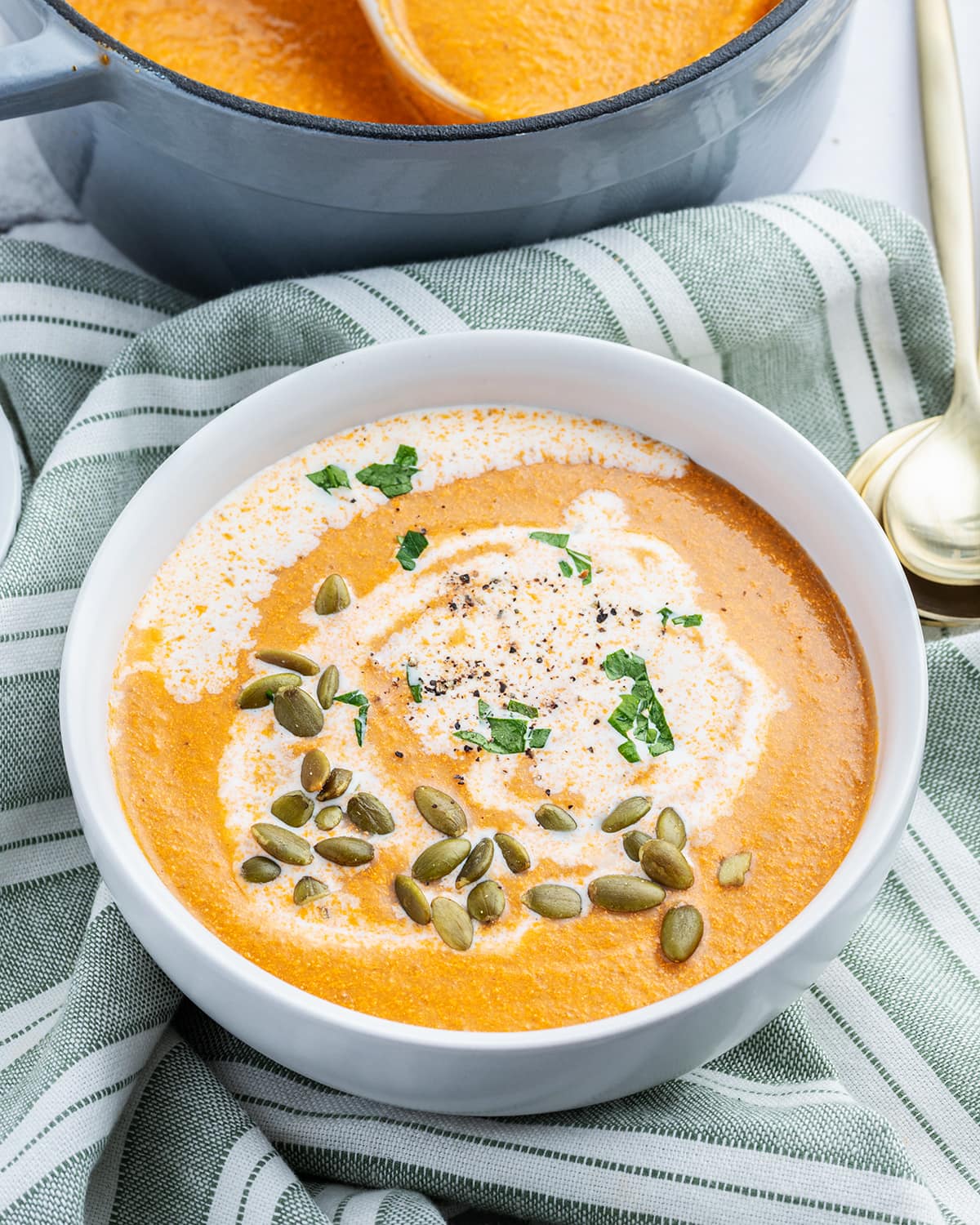 A bowl of tomato squash bisque topped with crunchy pumpkin seeds.