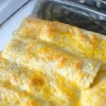 Angled view of easy green chile enchiladas in glass bakeware.