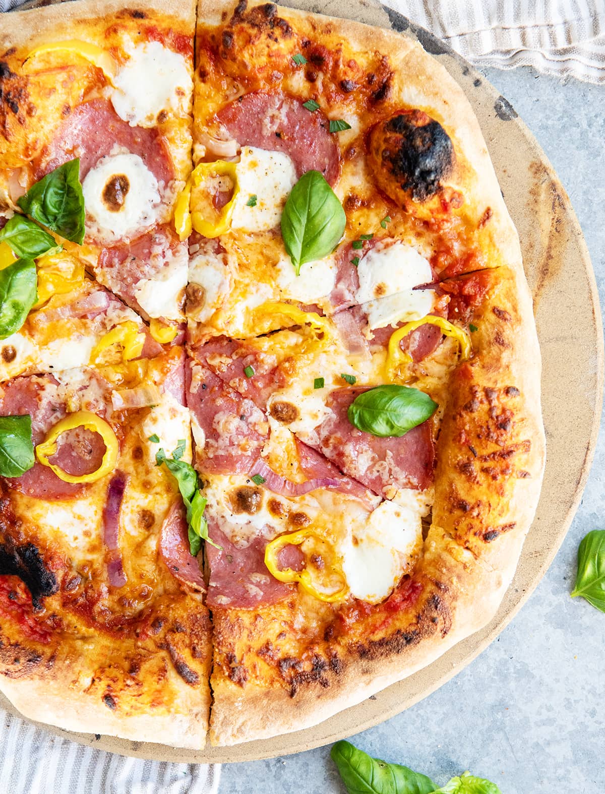 A sliced salami pizza with fresh mozzarella and fresh basil leaves.
