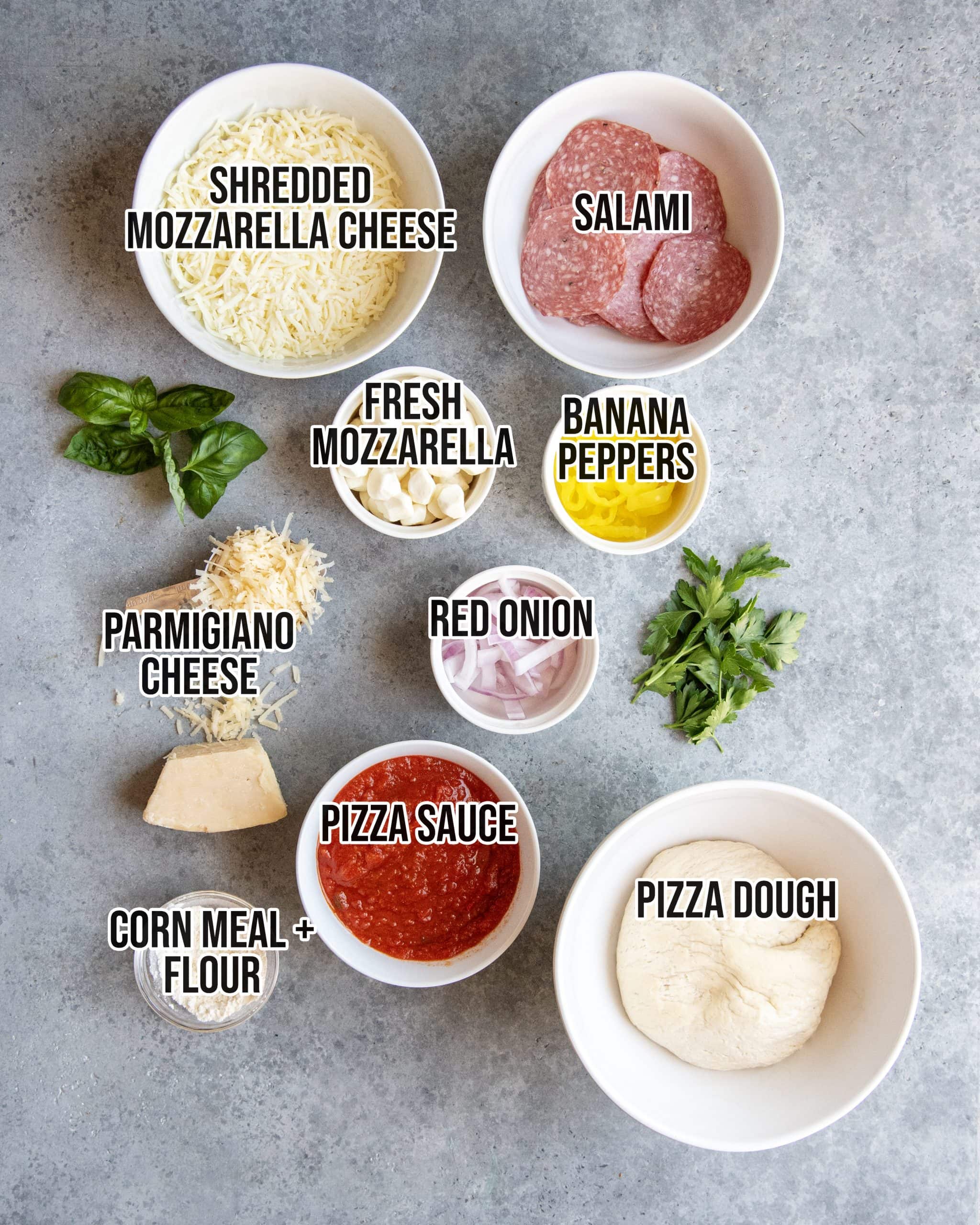 An overhead photo of the ingredients needed to make salami pizza.