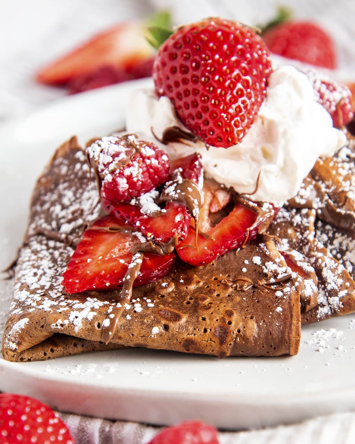 A close up of chocolate crepes folded up on a plate..