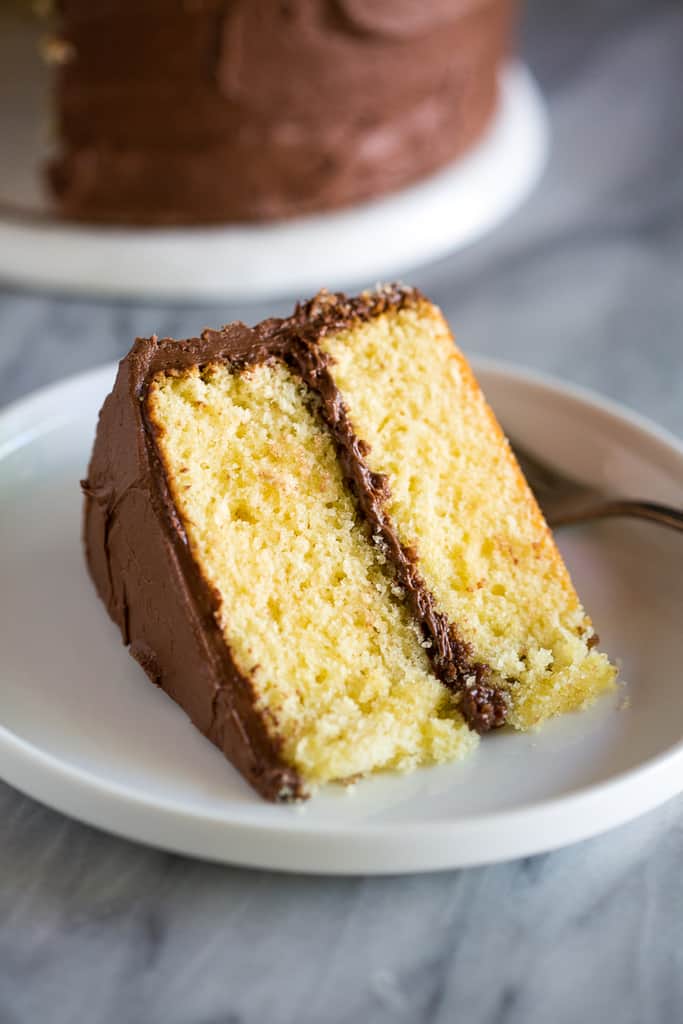 A slice of yellow cake with chocolate frosting