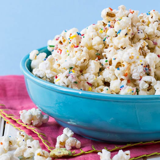 Cake batter popcorn is displayed in a blue bowl with sprinkles.