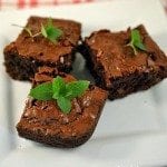 Angled view of chocolate mint brownies on a white plate.