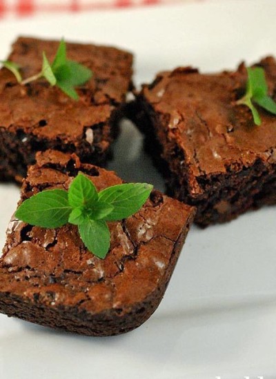 Angled view of chocolate mint brownies on a white plate.