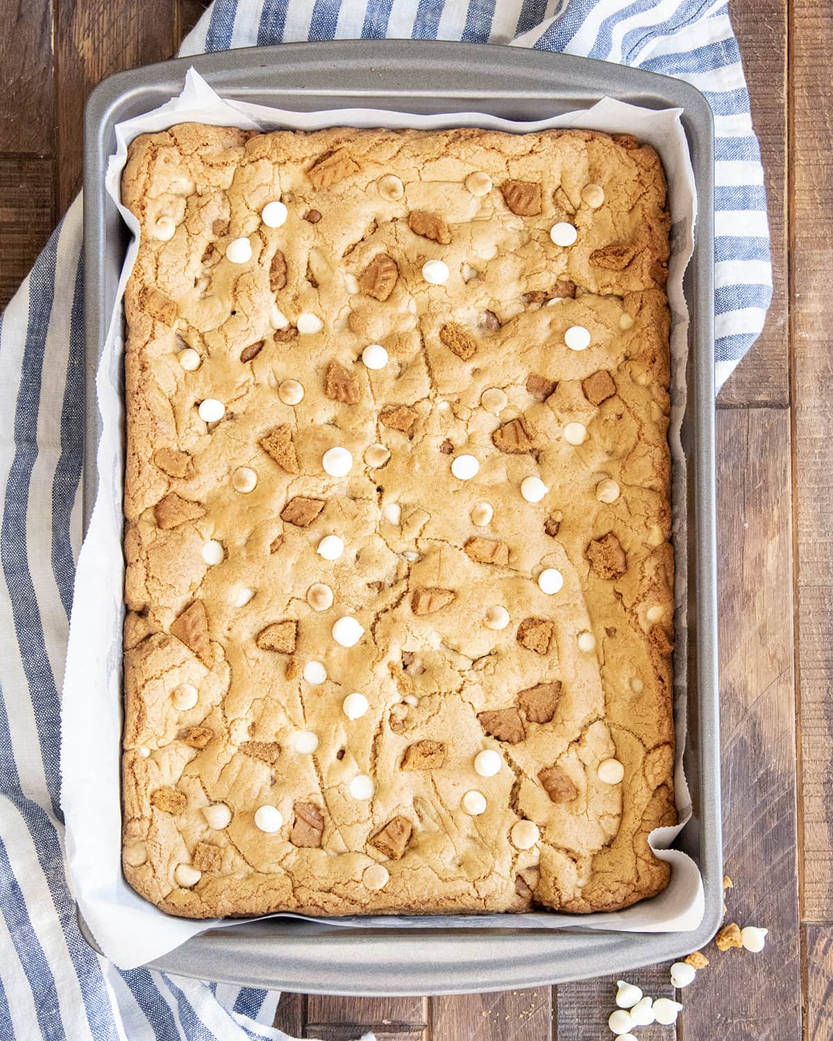 A pan of cookie bars topped with Biscoff cookie pieces and white chocolate chips.