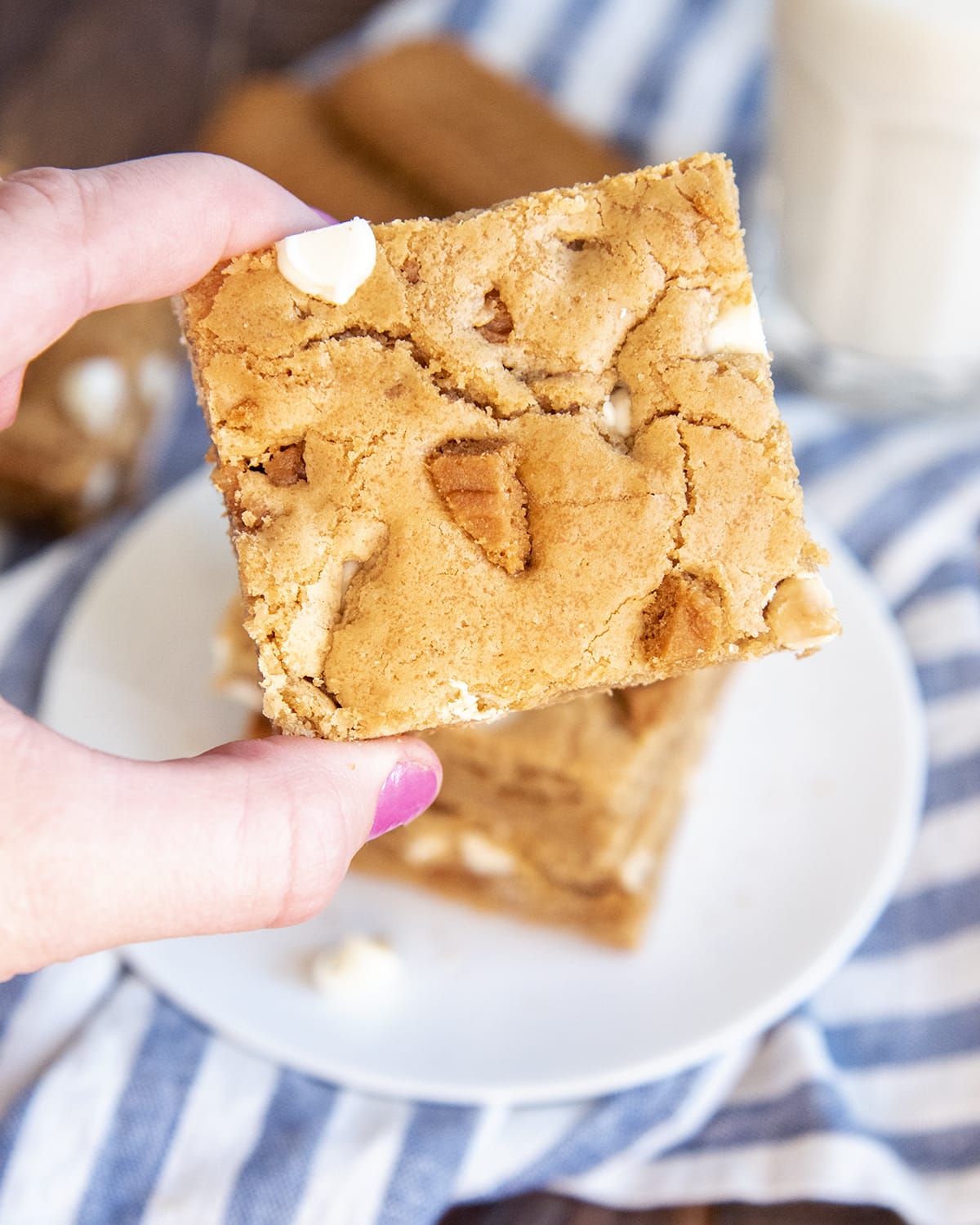 A hand holding a white chocolate chip Biscoff blondie.