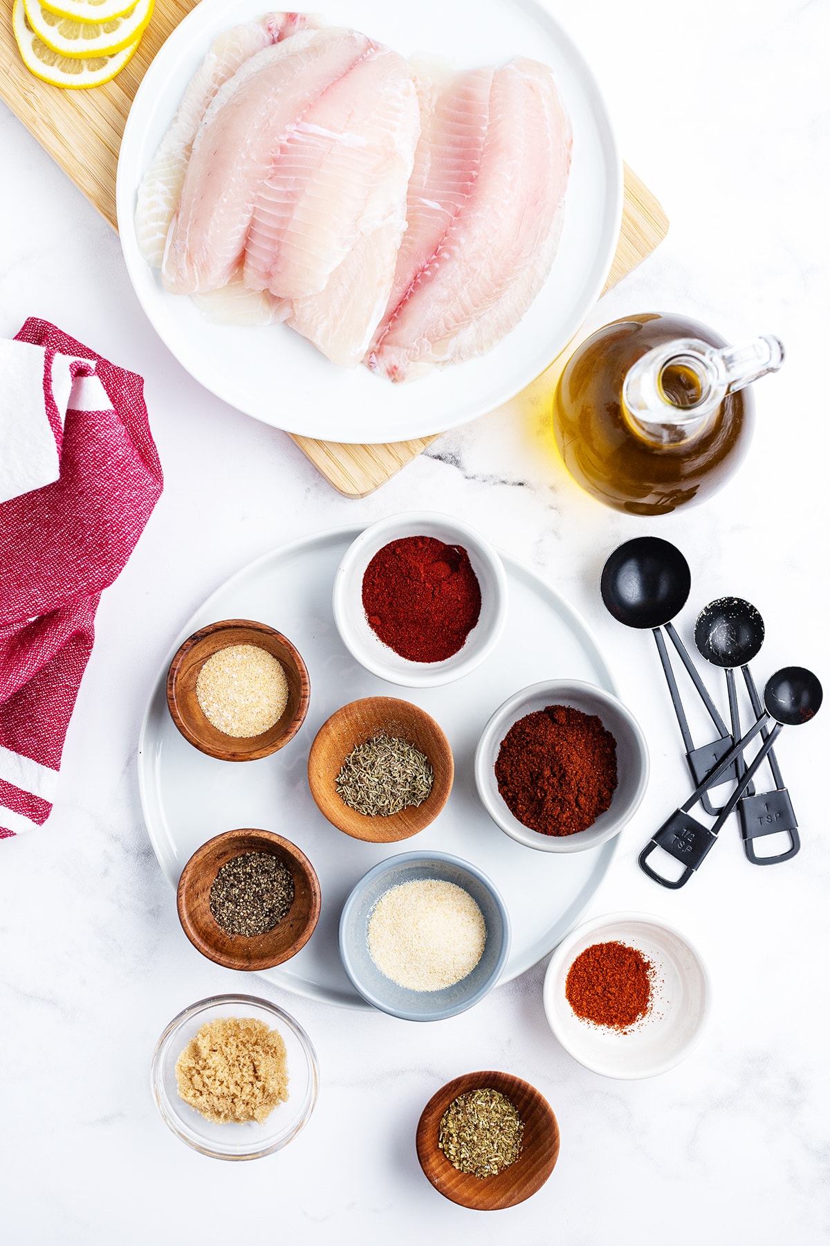 The ingredients needed to make blackened tilapia, tilapia, oil, and all the spices in little bowls.