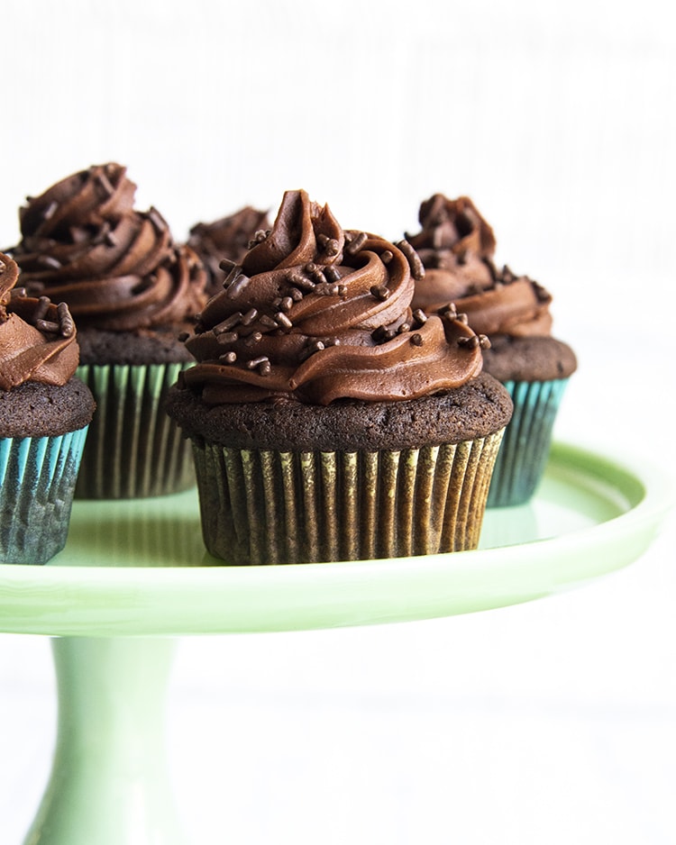 Chocolate cupcakes on a green cake stand.