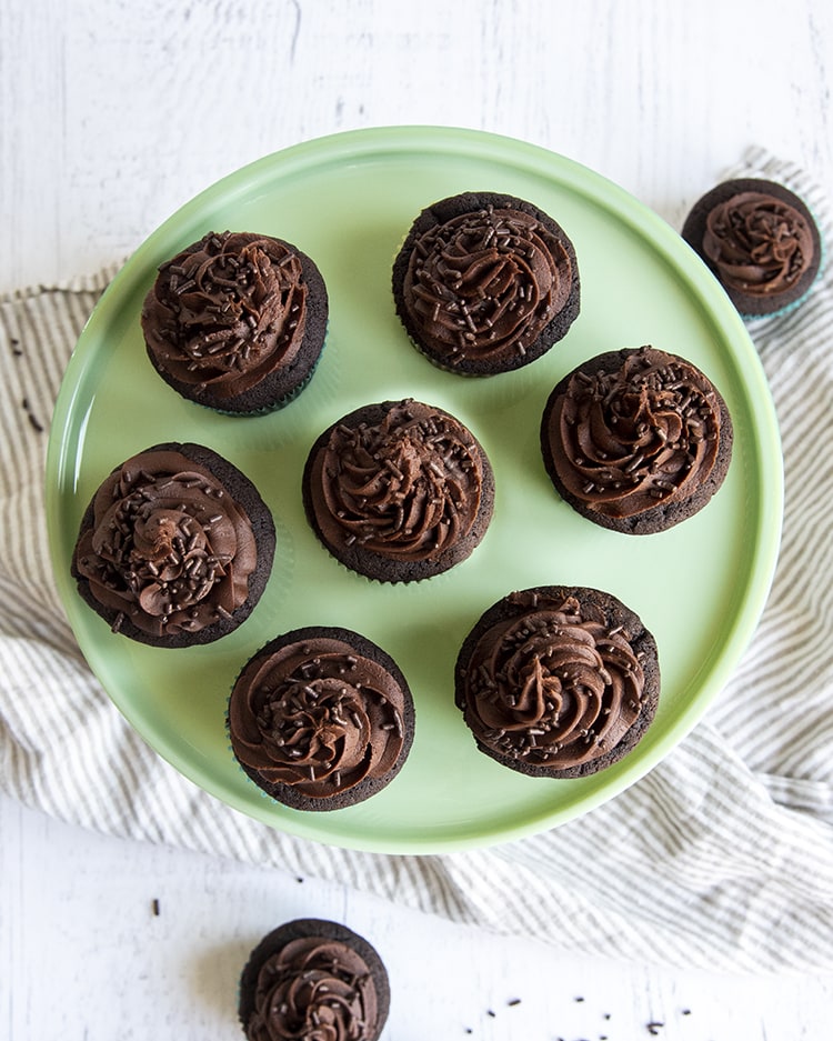 An overhead shot of chocolate cupcakes with chocolate buttercream frosting.