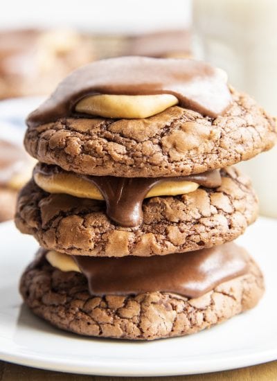 A stack of three buckeye brownie cookies with peanut butter and chocolate on top of the cookie.