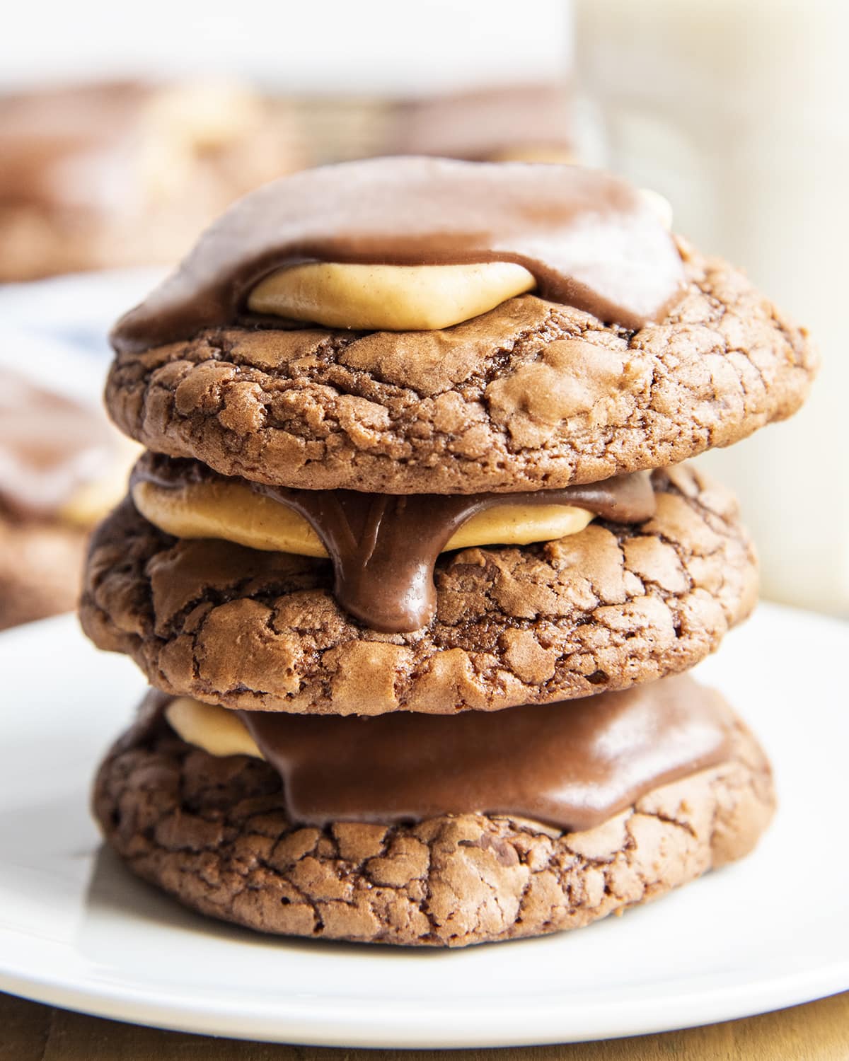 A stack of three buckeye brownie cookies with peanut butter and chocolate on top of the cookie.