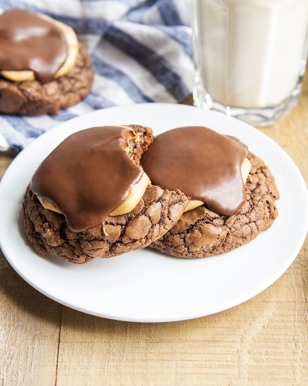 A plate with two buckeye brownie cookies topped with peanut butter and chocolate. One cookie has a bite out of it.