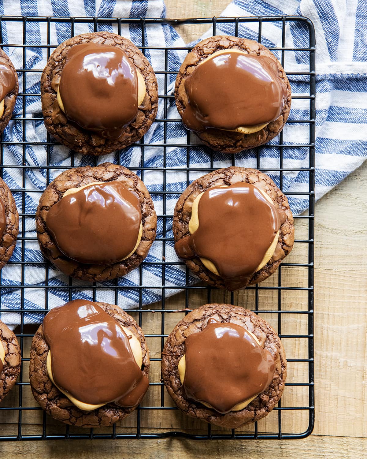 Rows of brownie cookies topped with peanut butter and melted chocolate over the top.