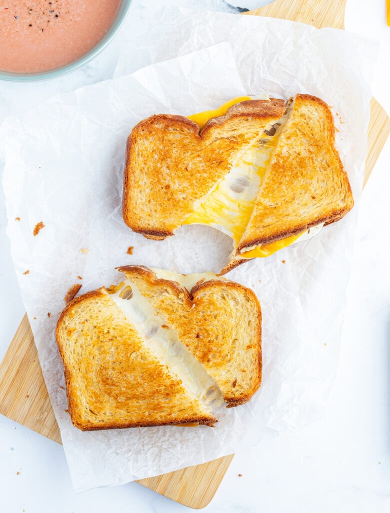 Two grilled cheese sandwiches on a piece of parchment paper.