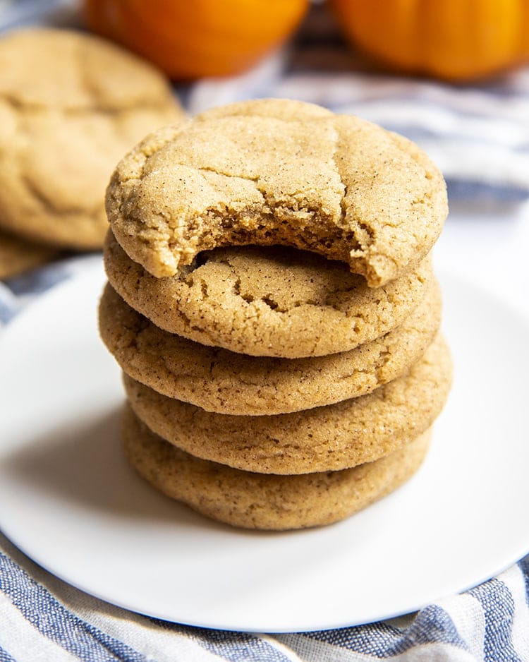 A stack of pumpkin snickerdoodle cookies. The top cookie has a bite taken out of it.