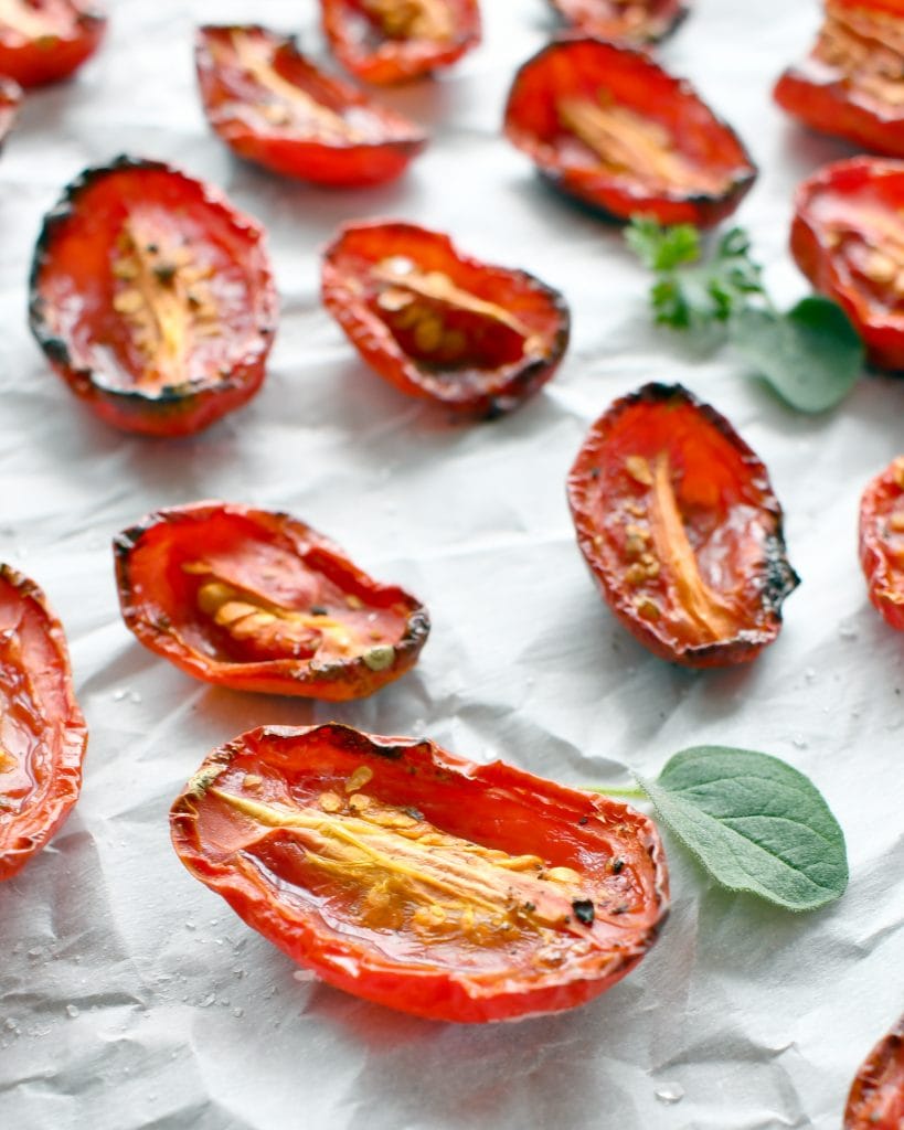 Angled view of roasted tomatoes on parchment paper.