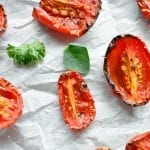 Close up view of roasted tomatoes on parchment paper.