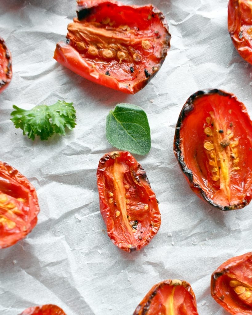 Close up view of roasted tomatoes on parchment paper.