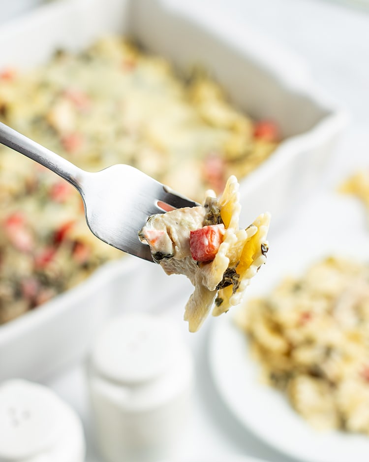 Close up image of spinach dip pasta being held with a silver fork.