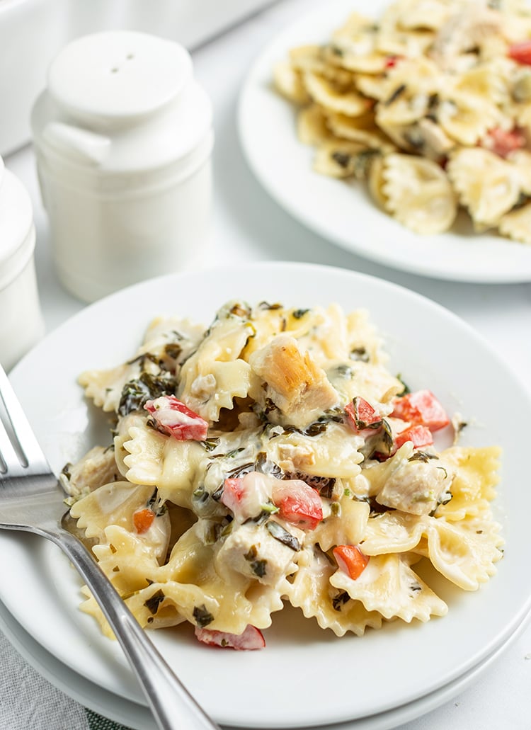 Close of image of spinach dip pasta in a bowl with a fork.