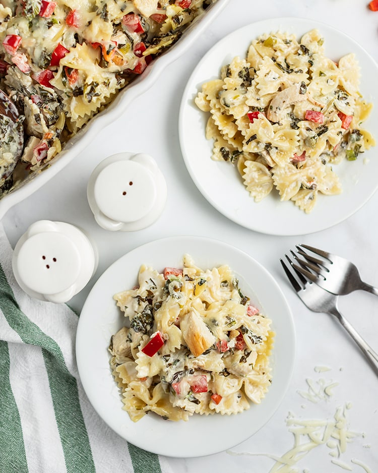 Above image of multiple plates of spinach dip pasta with forks.