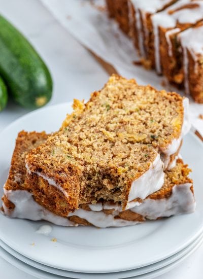 A plate of two slices of pineapple zucchini bread , the top slice has a bite out of it.