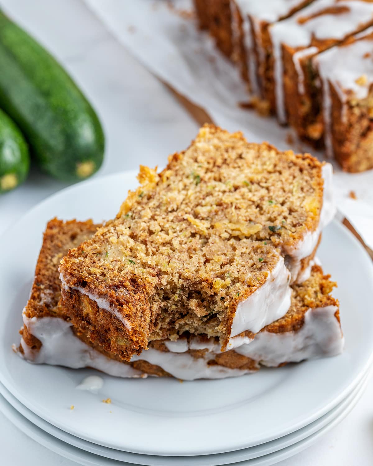 A plate of two slices of pineapple zucchini bread , the top slice has a bite out of it.