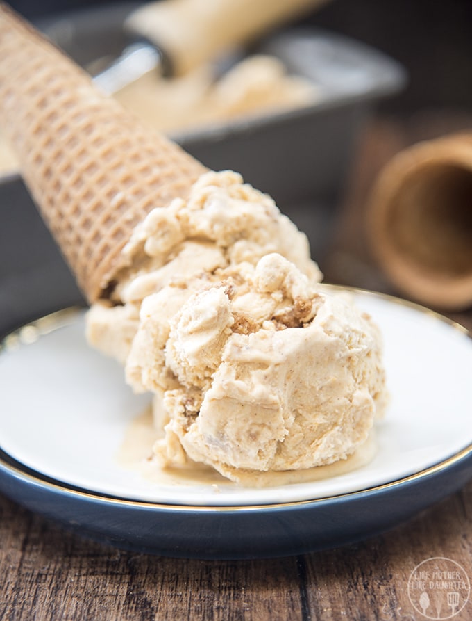 An ice cream cone of pumpkin ice cream that is upside down on a plate. 