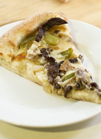 Top view of philly cheese steak pizza on a white plate.