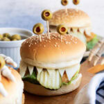 A chicken sandwich with three green olives on top to look like monster eyes.