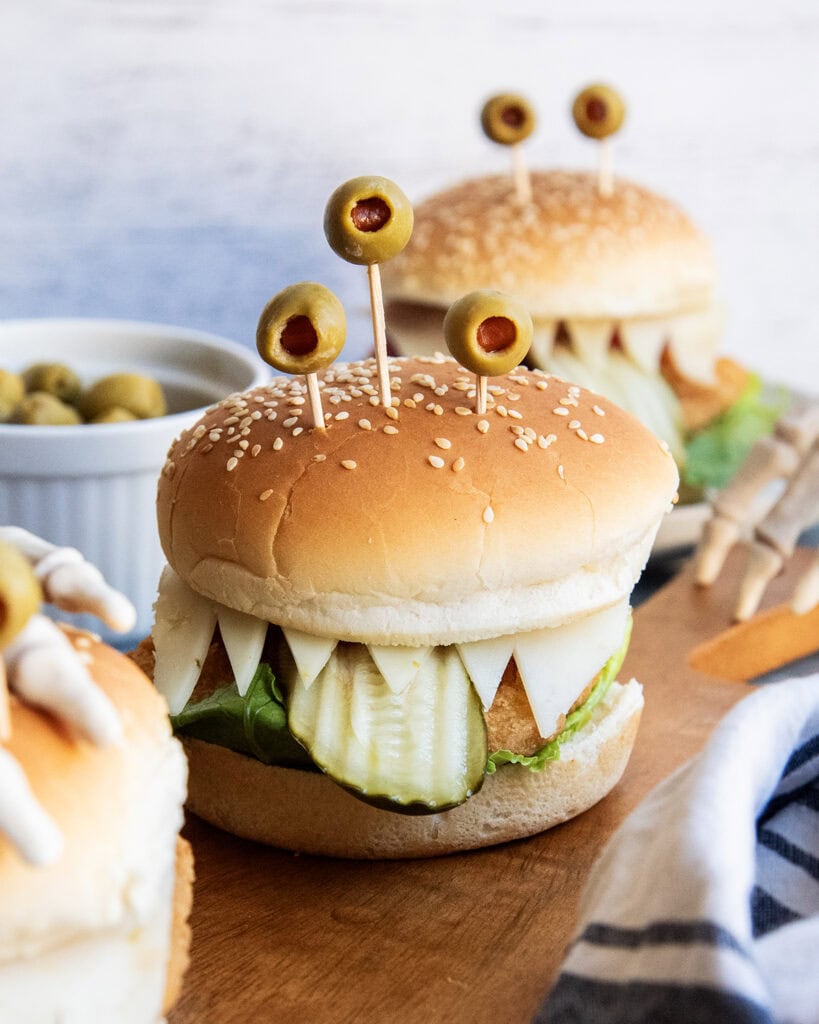 A chicken sandwich with three green olives on top to look like monster eyes.