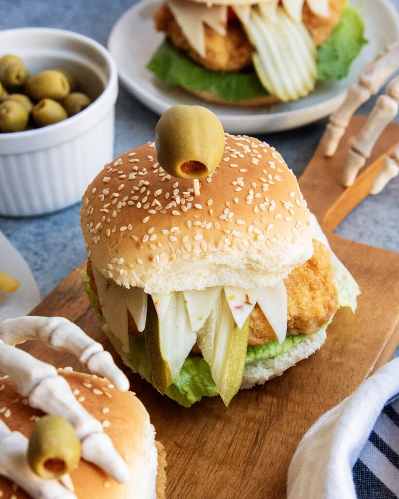 A chicken sandwich with one green olives on top to look like monster eyes.