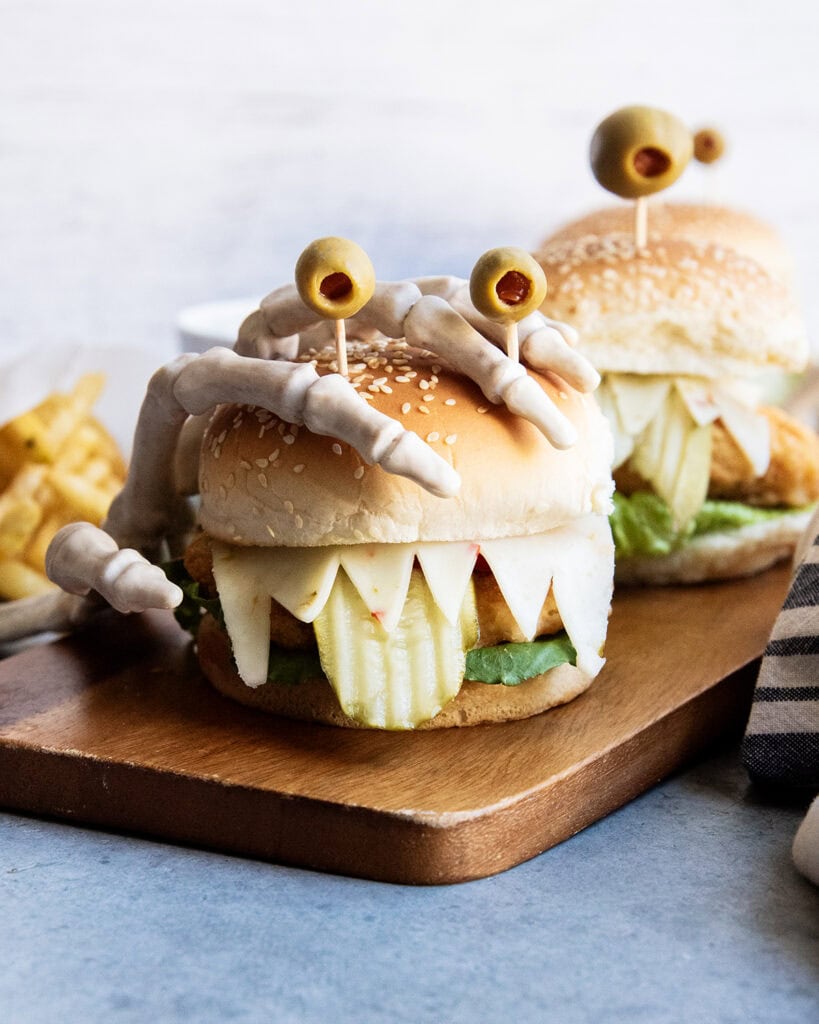 A chicken sandwich with a skeleton hand holding it.