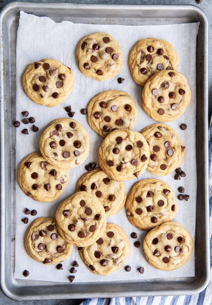 A pile of chocolate chip cookies on a baking sheet.