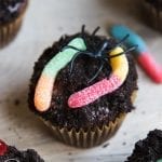 A chocolate dirt cupcake covered in chocolate frosting, Oreo crumbles, and gummy worms.