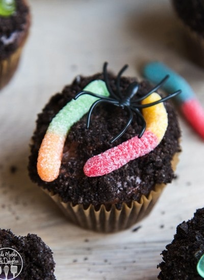 A chocolate dirt cupcake covered in chocolate frosting, Oreo crumbles, and gummy worms.