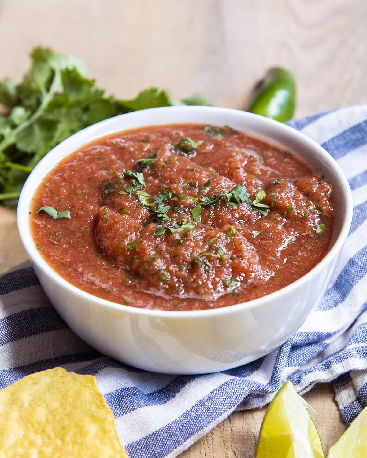 A white bowl full of a red salsa, with cilantro pieces on top.