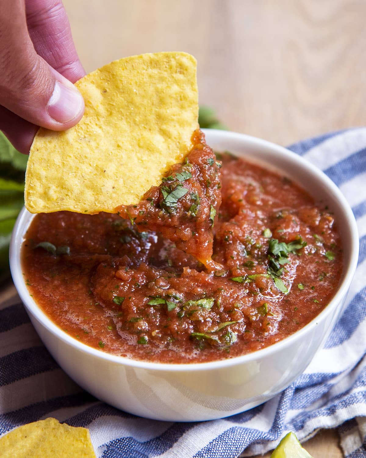A bowl of salsa with a chip dipping into it.