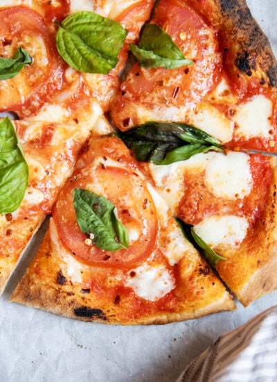 An above view of a tomato margherita pizza with fresh basil.