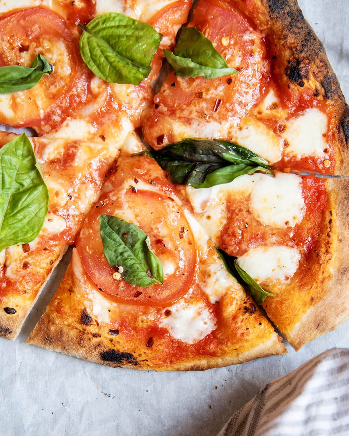 An above view of a tomato margherita pizza with fresh basil.