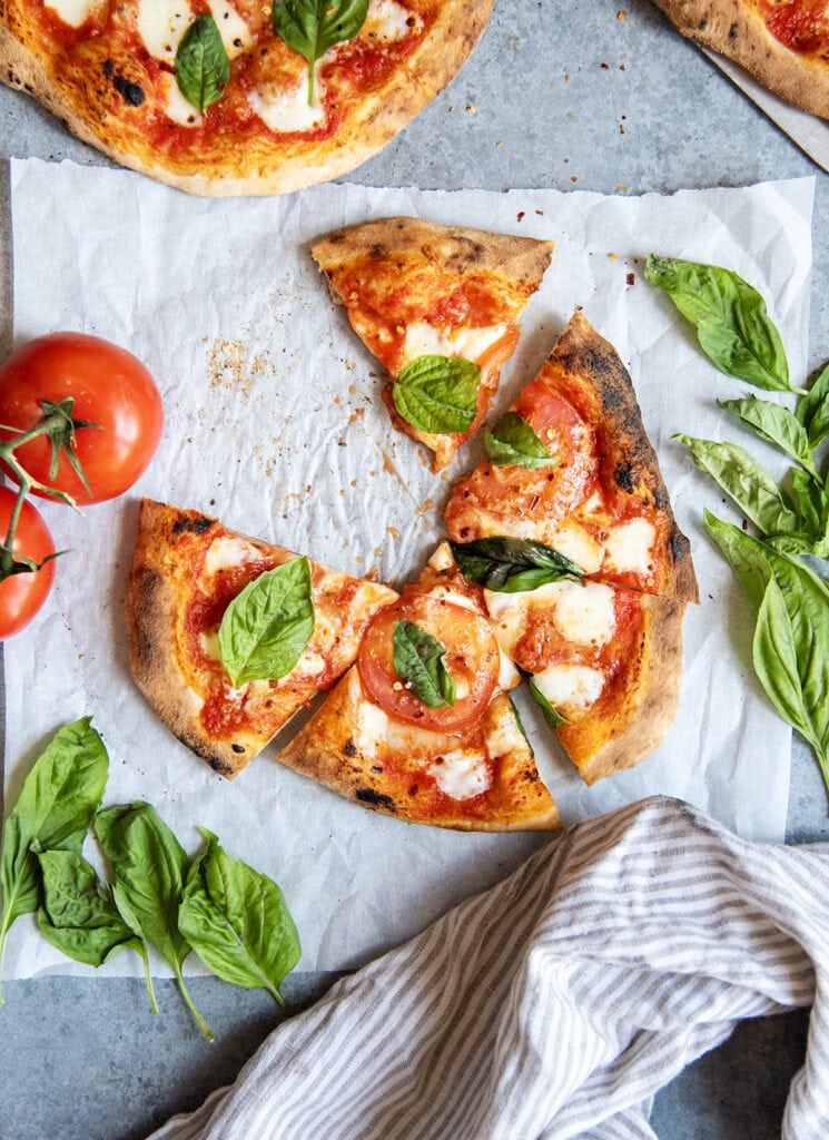 An above view of a tomato basil pizza with a slice removed from the pizza. 