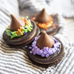 Three oreos topped with hershey's kisses and decorated to look like witch hats.