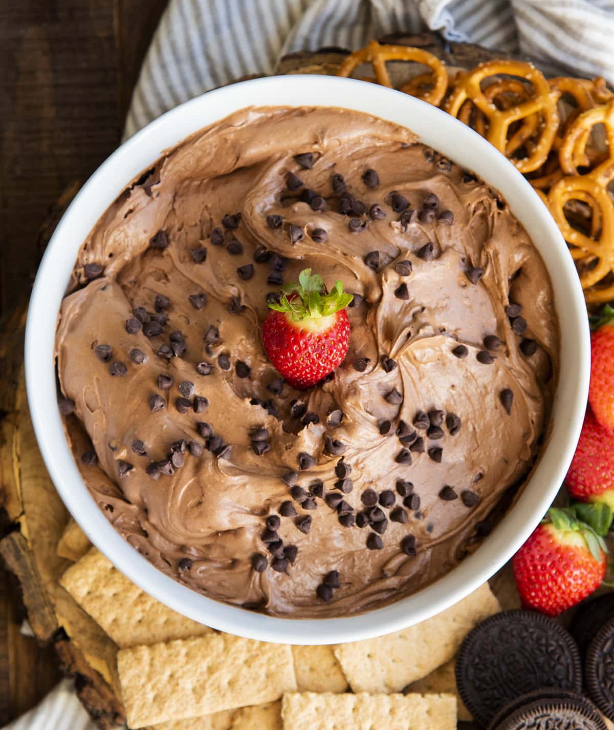 An overhead photo of a bowl of brownie batter dip topped with mini chocolate chips and a red strawberry in the middle. 