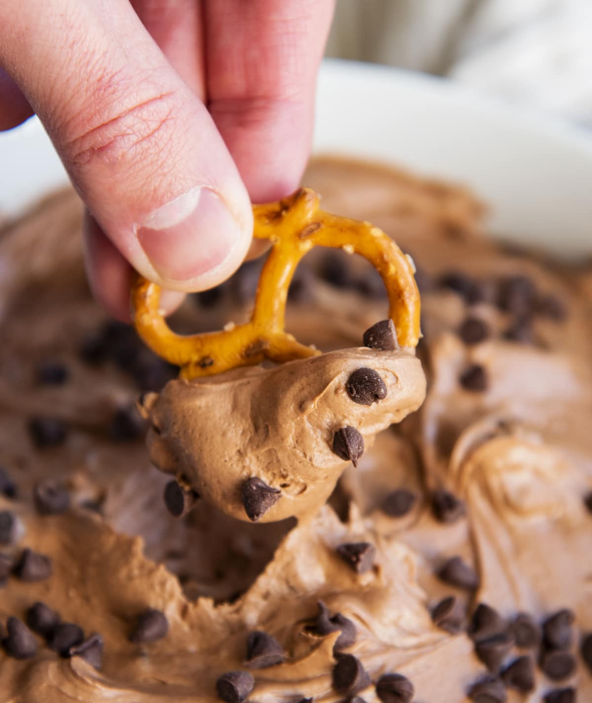 A pretzel topped with brownie dip and mini chocolate chips.