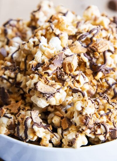 A close up of Butterfinger popcorn with Butterfinger pieces and chocolate drizzle.