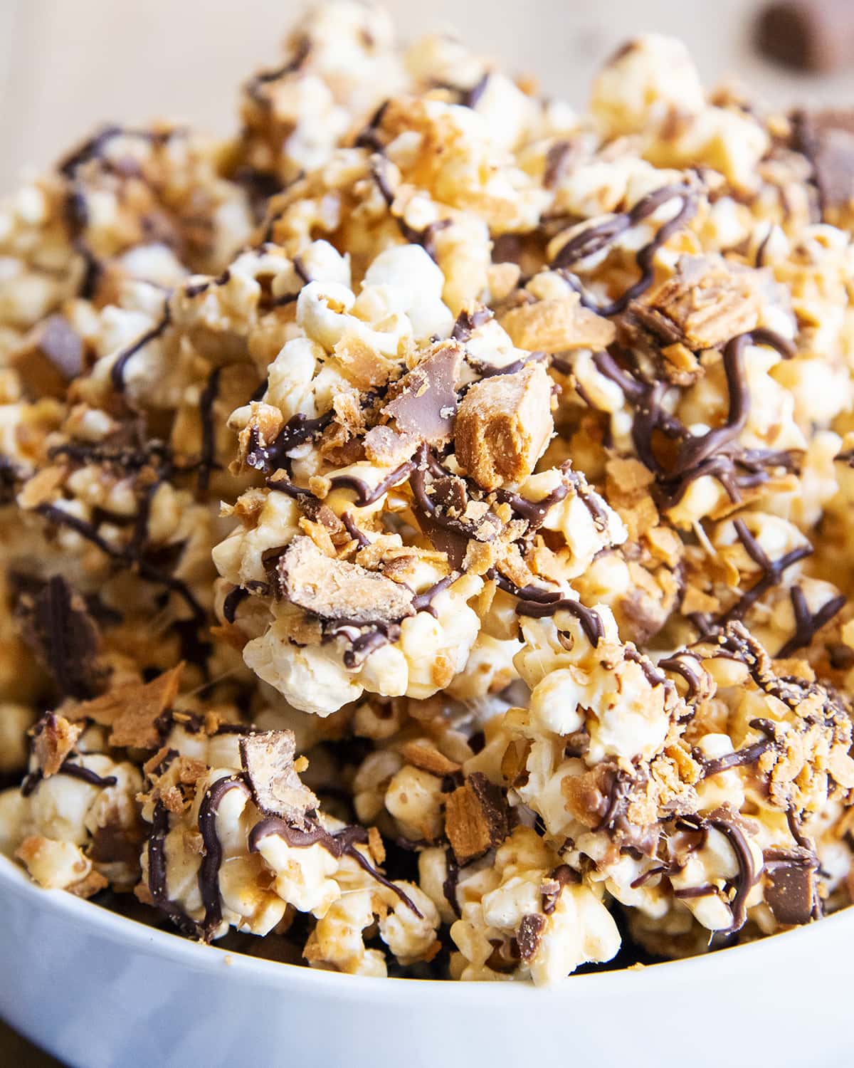 A close up of Butterfinger popcorn with Butterfinger pieces and chocolate drizzle.