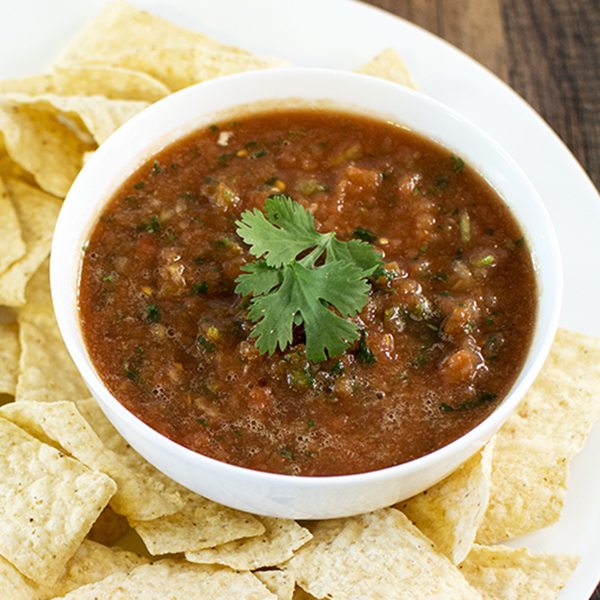 Angled view of restaurant style salsa in a white bowl with chips.