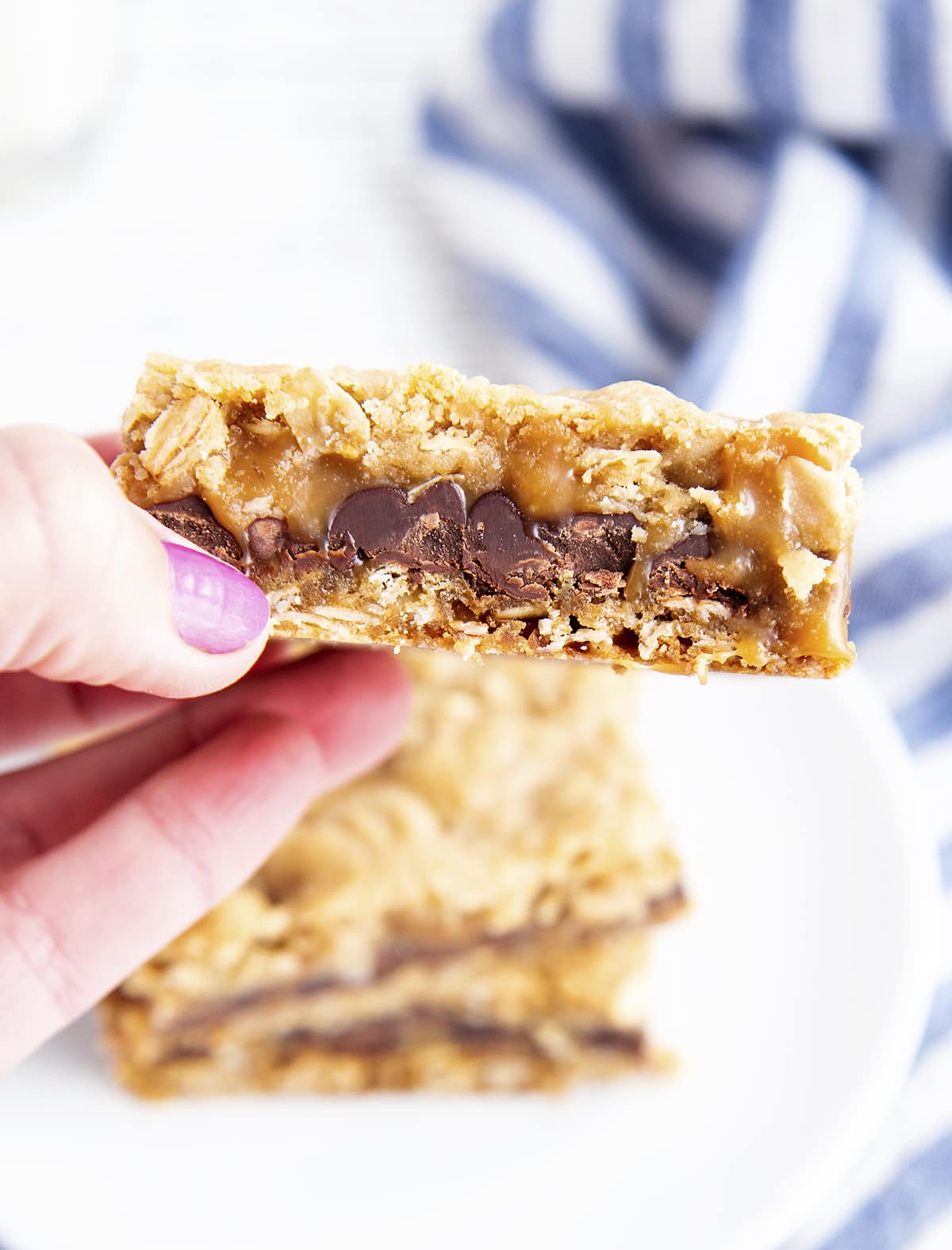 A hand holding a chocolate caramel oatmeal bar.