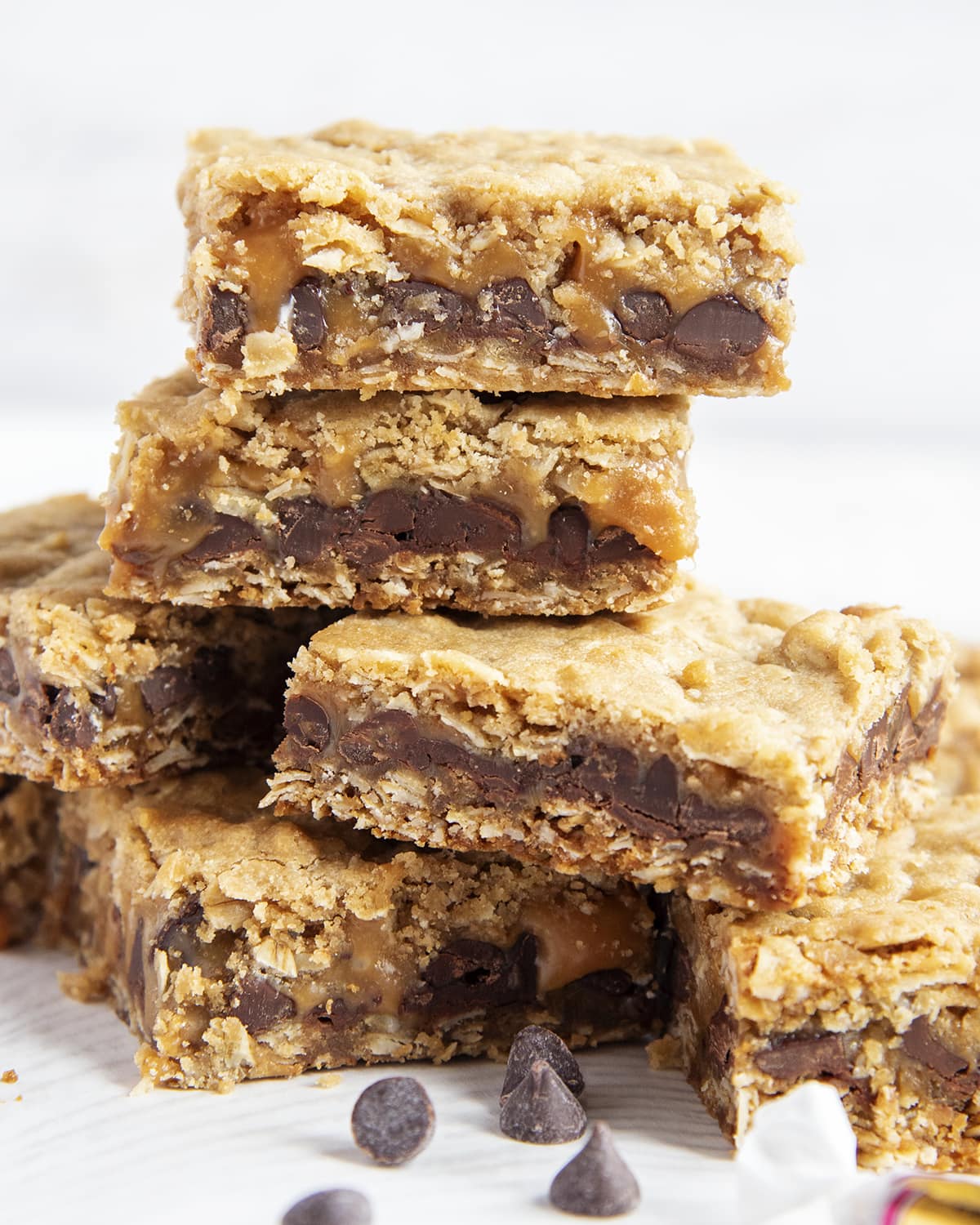 A stack of oatmeal cookie bars with chocolate and caramel in the middle. 